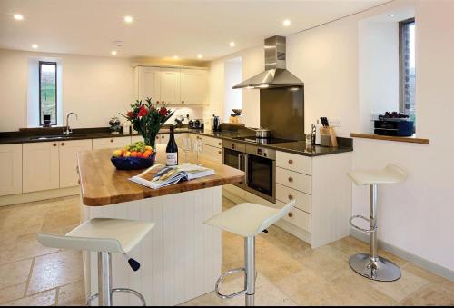 a kitchen with a counter and stools in it at Blagdon Lower Barn in Winterborne Steepleton