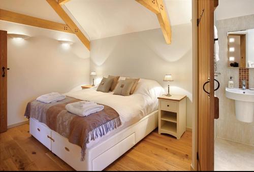 1 dormitorio con 1 cama y baño con lavamanos en Blagdon Lower Barn, en Winterborne Steepleton