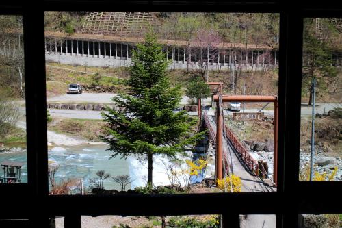a view from a window of a tree and a bridge at Shinzanso in Takayama