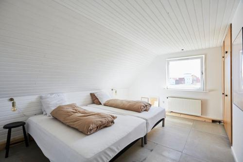 Apartment with a unique view في Vestervig: سريرين في غرفة بجدران بيضاء ونافذة