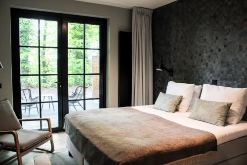 een slaapkamer met een bed, een stoel en een raam bij Veluwe Hotel De Beyaerd in Hulshorst