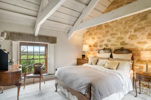 a bedroom with a large bed and a stone wall at Tregadjack Farmhouse in Crowan