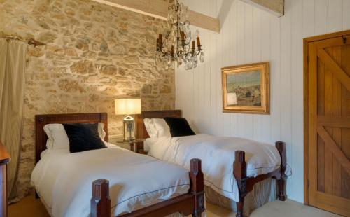 two beds in a bedroom with a stone wall at Tregadjack Barn in Crowan