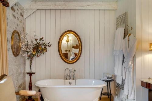 a bathroom with a white tub and a mirror at Tregadjack Barn in Crowan