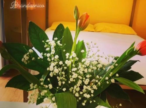 a vase of flowers on a table next to a bed at Le Stanze Di Brando E Nico in Tricase