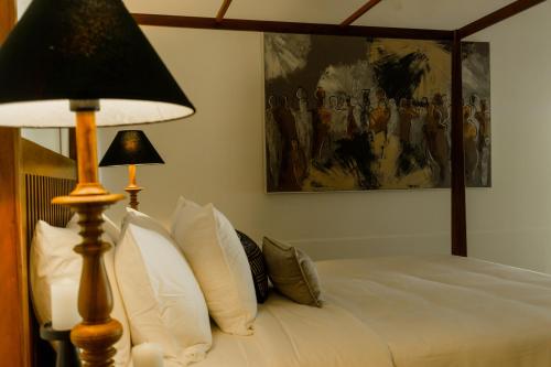 a bedroom with a bed with a lamp and a painting at The Well House Galle Sri Lanka in Unawatuna