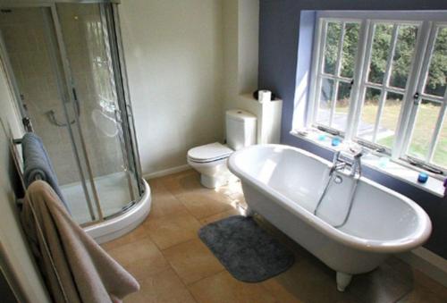 a bathroom with a tub and a shower and a toilet at The Oaks in All Stretton