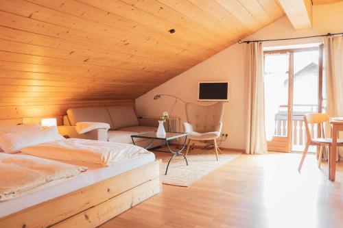 1 dormitorio con techo de madera, cama y sofá en Landhaus Alger, en Immenstadt im Allgäu