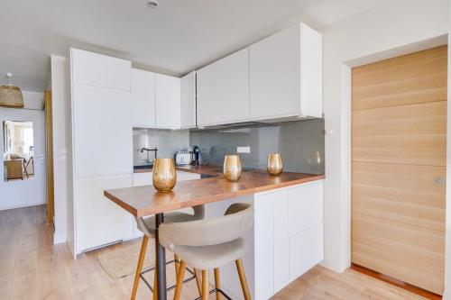 une cuisine avec des armoires blanches et une table en bois dans l'établissement Flat in the port of Arcachon, à Arcachon