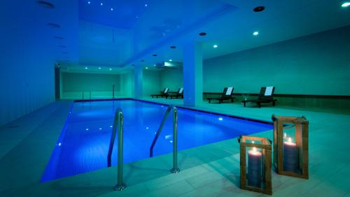 a large swimming pool in a building with blue lighting at Relais & Châteaux Hotel Quadrille - Adults Only in Gdynia