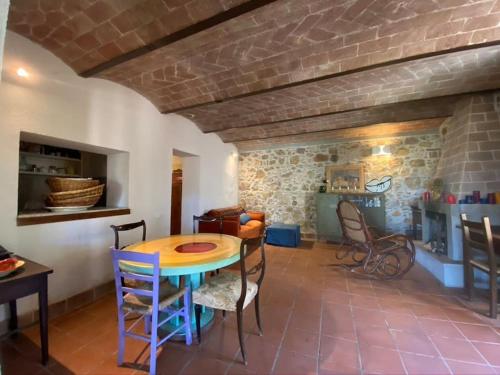 Cette chambre dispose d'une table, de chaises et d'un mur en briques. dans l'établissement Podere Bellavista in campagna, à Gabbro