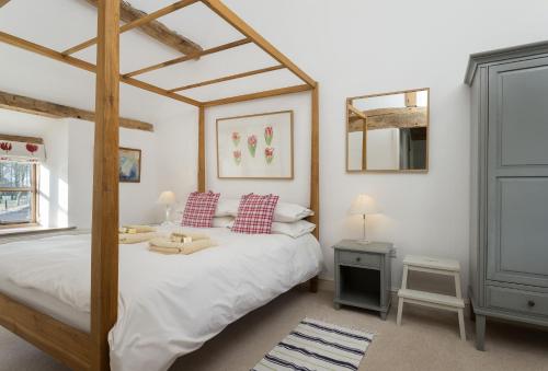 a bedroom with a large bed with a wooden canopy at Hampton Wafre Cottage in Leominster