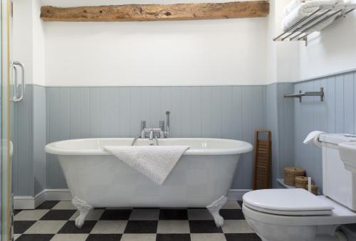 a bathroom with a white tub and a toilet at Hampton Wafre Cottage in Leominster
