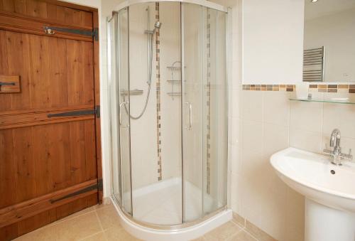 a bathroom with a glass shower and a sink at Harvest Moon in Honiton