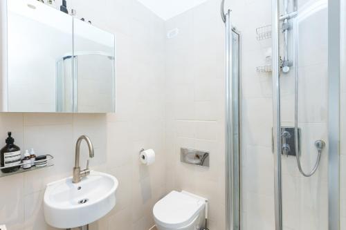 a white bathroom with a sink and a shower at Light filled studio with view of Regents Park in London