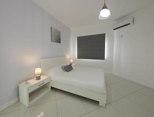 Dormitorio blanco con cama, mesita de noche y lámpara en Oceanview 3-bedroom apartment, en Flic en Flac
