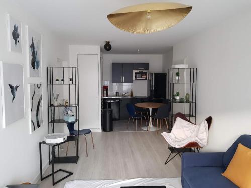 sala de estar con sofá azul y cocina en Appart neuf entre Paris et Versailles, A 5 mn école Ducasse, en Meudon