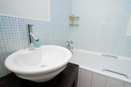 a bathroom with a white sink and a bath tub at Bryn Rhydd in Eglwys-Fâch