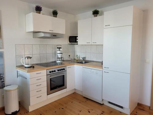 a white kitchen with white cabinets and a stove at 4 Sterne Dtv Floating House in Kröslin