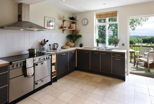 a kitchen with black and white appliances and a patio at Upper Mowley in Kington
