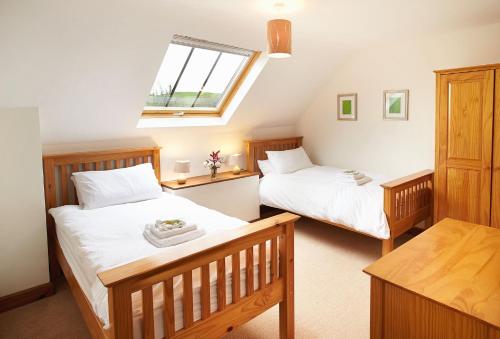 sypialnia z 2 łóżkami i oknem w obiekcie Lower Curscombe Barn w mieście Honiton