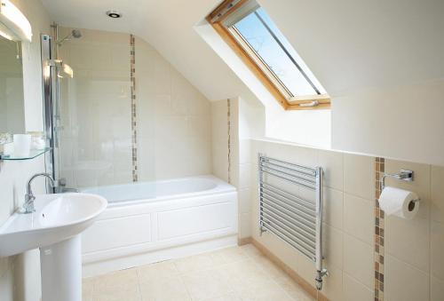 łazienka z umywalką, wanną i oknem w obiekcie Lower Curscombe Barn w mieście Honiton