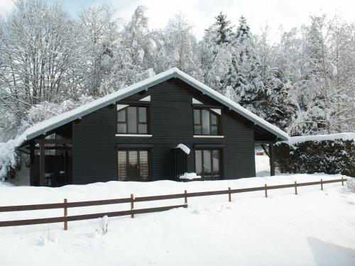uma casa preta na neve com uma cerca em Les Chalets Du Pres D'amont em Vagney