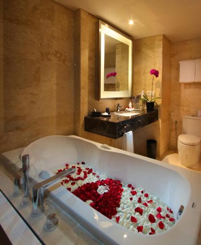 a bath tub filled with red flowers in a bathroom at Sovereign Bali Hotel in Kuta