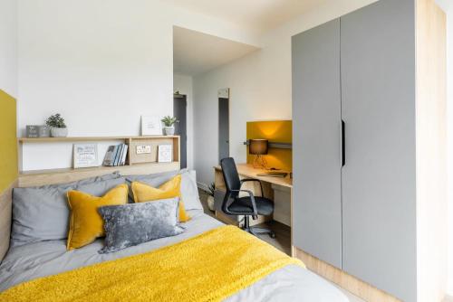a bedroom with a bed with yellow and gray pillows at For Students Only Modern Studios and Ensuite Bedrooms with Shared Kitchen at Hillfort House in Brighton in Brighton & Hove