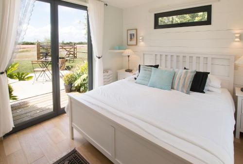 a bedroom with a large white bed and a balcony at Cherrystone Barn in Chalvington