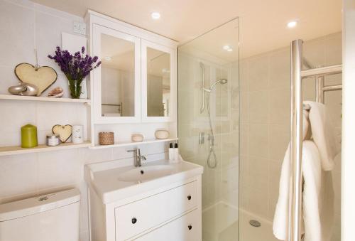 a white bathroom with a sink and a shower at Cherrystone Barn in Chalvington