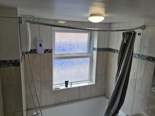 a bathroom with a window and a shower curtain at Lovely Property in London