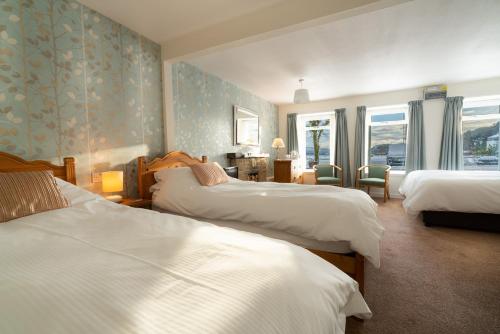a hotel room with three beds and a window at Harbour Guest House in Tobermory