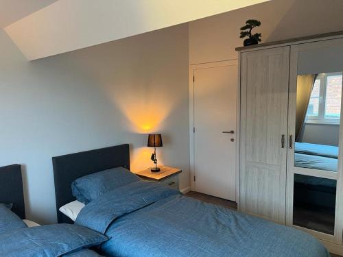 a bedroom with a blue bed and a night stand with a lamp at Happy Home Eeklo in Centre in Eeklo