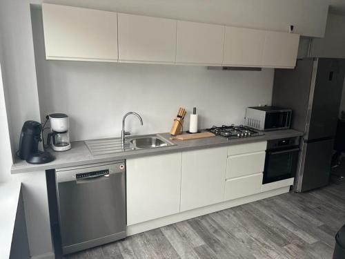 a kitchen with white cabinets and a sink at Happy Home Eeklo in Centre in Eeklo