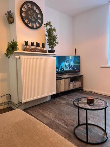 a living room with a tv and a table and a clock at Happy Home Eeklo in Centre in Eeklo