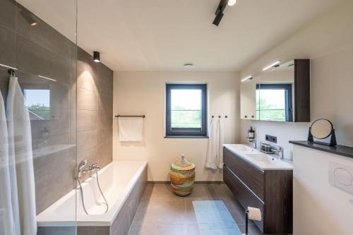 La salle de bains est pourvue d'une baignoire et d'un lavabo. dans l'établissement unique hideaway, holiday house with large garden, à Kortenaken