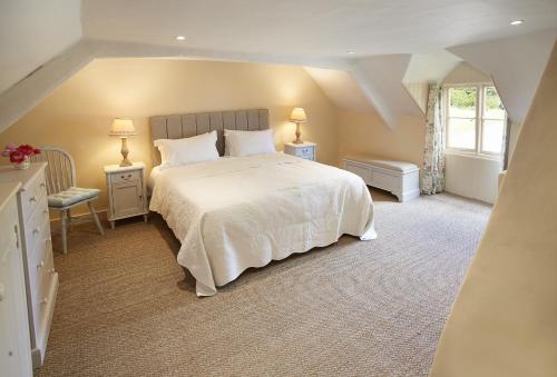 Un dormitorio con una gran cama blanca y una ventana en Librarian's Cottage en Coneysthorpe