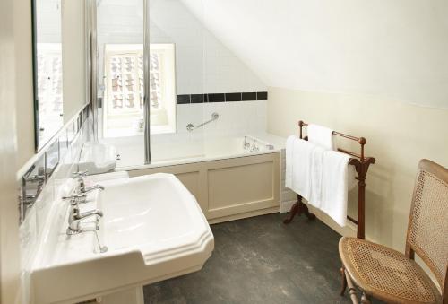 a white bathroom with a sink and a tub at Librarian's Cottage in Coneysthorpe