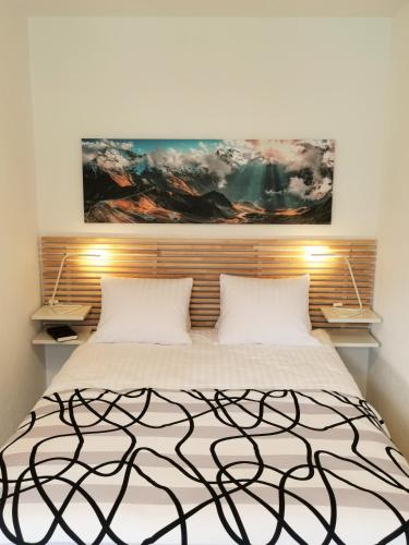 a bedroom with a bed with a painting above it at Hotel Brienzersee in Ringgenberg