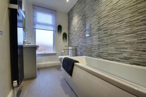 a bathroom with a tub and a stone wall at Birkdale boutique Apartment in Southport