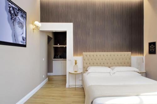 a bedroom with two white beds and a kitchen at Il Borgo Luxury Suites in Nettuno
