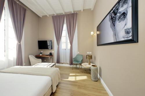a bedroom with a bed and a tv on a wall at Il Borgo Luxury Suites in Nettuno