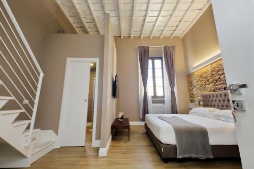 a bedroom with a large bed and a staircase at Il Borgo Luxury Suites in Nettuno