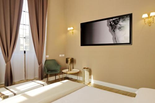 a bedroom with a bed and a tv on the wall at Il Borgo Luxury Suites in Nettuno