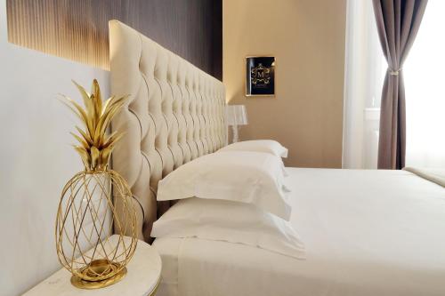 a bedroom with a white bed with a large headboard at Il Borgo Luxury Suites in Nettuno