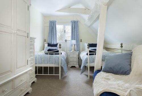 a white bedroom with two beds and a window at Cobbler's Cottage in Pembridge