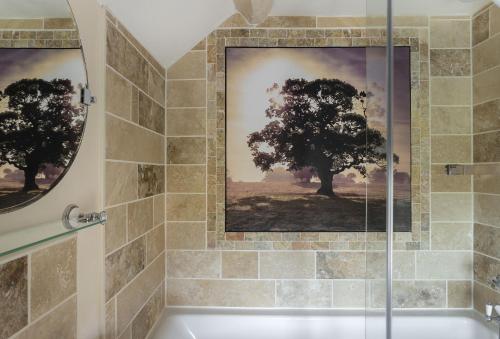 a bathroom with a shower and a painting of trees at Cobbler's Cottage in Pembridge