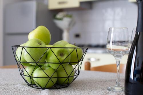 a bowl of green apples next to a glass of wine at Casa Merano Residence & Restaurant Bibione Centro in Bibione