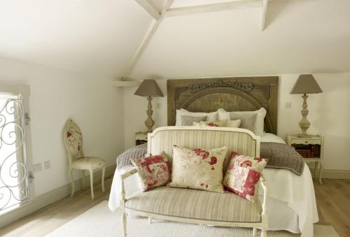 a bedroom with a bed with a chair and pillows at Rectory Cottage in Stamford
